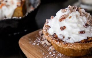 A rich pecan pie topped with whipped cream, the perfect ending to any meal at The Pioneer BBQ.