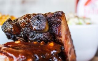 Juicy, perfectly smoked ribs showcasing the authentic Texas style barbecue at The Pioneer BBQ.